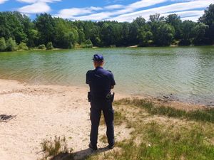Policjant na tle zbiornika wodnego.