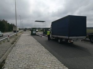 Na zdjęciu pierwszym widoczny jest pojazd ciężarowy, przy którym stoi policjant. W dalszym planie widać mobilna stacje kontroli pojazdów. Na drugim zdjęciu widać pojazdy policji, Inspekcji Transportu Drogowego , a w oddali stojących funkcjonariuszy i samochód ciężarowy.