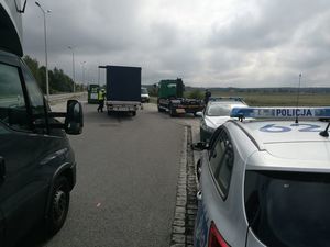 Na zdjęciu pierwszym widoczny jest pojazd ciężarowy, przy którym stoi policjant. W dalszym planie widać mobilna stacje kontroli pojazdów. Na drugim zdjęciu widać pojazdy policji, Inspekcji Transportu Drogowego , a w oddali stojących funkcjonariuszy i samochód ciężarowy.