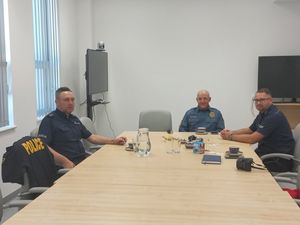 Policjanci bolesławieckiej komendy i amerykański policjant siedzący przy stole.