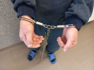 Kajdanki zespolone założone na rękach i nogach mężczyzny.
