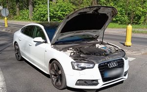 Biały samochód osobowy marki Audi z podniesioną klapą silnika.