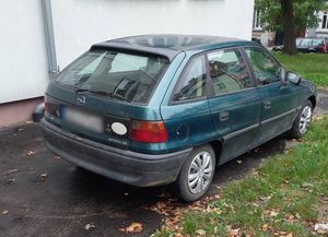 Odzyskany pojazd marki Opel Astra, stojący przy budynku.