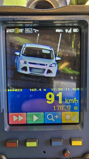 Zdjęcie z pomiaru prędkości białego pojazdu widocznego na ekranie miernika prędkości.