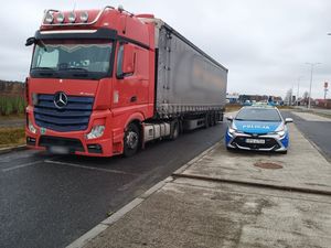 Zestaw ciężarowy z czerwona kabiną oraz radiowóz.